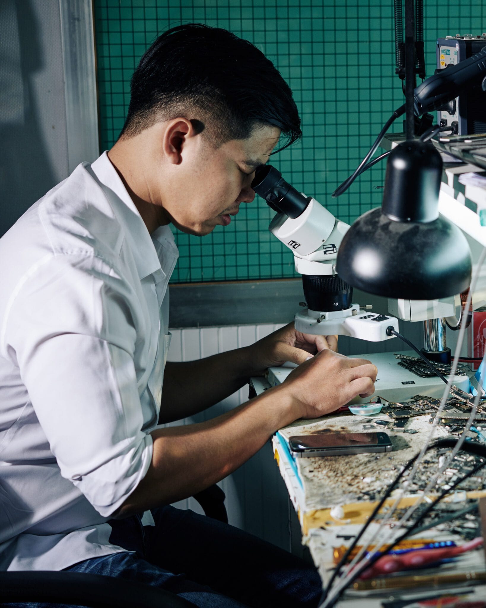 Repairman using microscope when fixing small details in smartphone